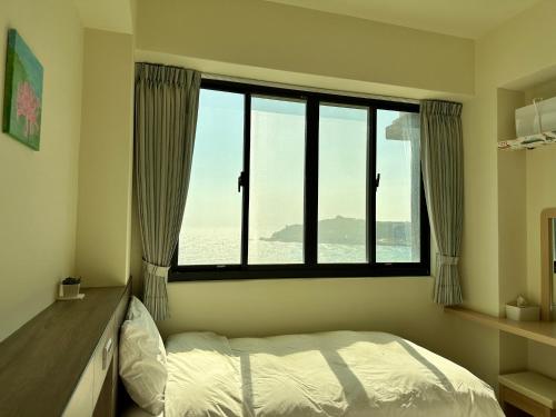東引鄉的住宿－東引海悅樓民宿，一间卧室设有一张床和一个大窗户