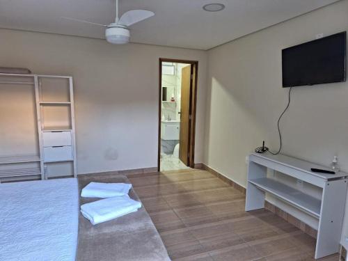 Pokój z telewizorem i łóżkiem z ręcznikami w obiekcie Pousada Saint James w mieście Águas de Lindóia