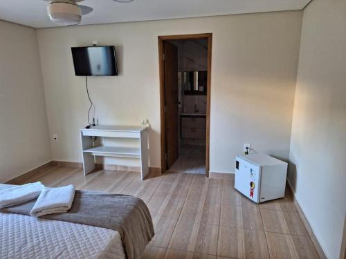 a bedroom with a bed and a desk and a television at Pousada Saint James in Águas de Lindóia