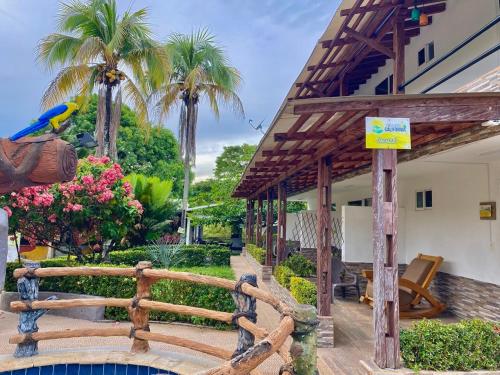 a wooden fence next to a house with palm trees at Finca Hotel California Doradal in Doradal