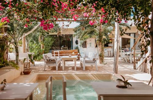 een patio met een tafel en stoelen en roze bloemen bij LunArena Boutique Beach Hotel Yucatan Mexico in El Cuyo