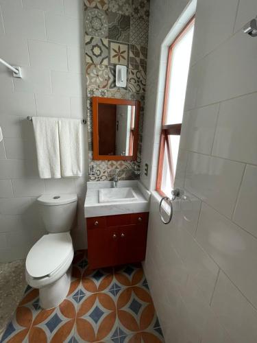 uma casa de banho com um WC, um lavatório e um espelho. em Casa Sol em Oaxaca de Juárez