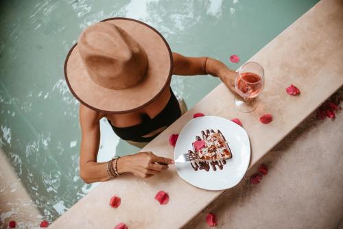 a woman in a hat sitting at a table with a glass of wine at LunArena Barefoot Comfort in El Cuyo