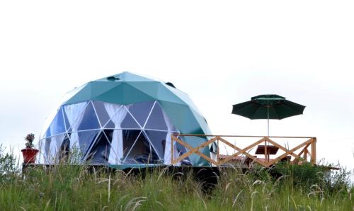 a dome tent with a table and an umbrella at glamping casa blanca in Guatavita