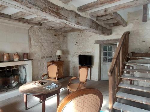 - un salon avec un escalier, une table et des chaises dans l'établissement Gîte de charme avec jardin au cœur des châteaux, WiFi, parking inclus - FR-1-381-543, à Benais