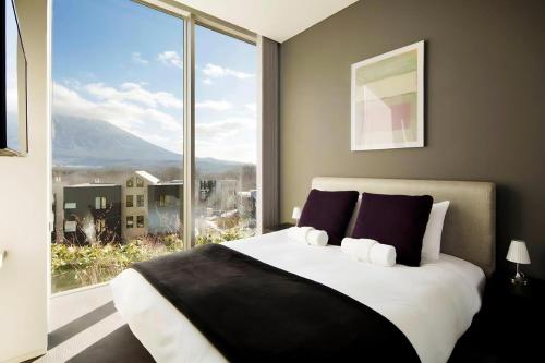 a bedroom with a large bed with a large window at Terrazze in Kutchan