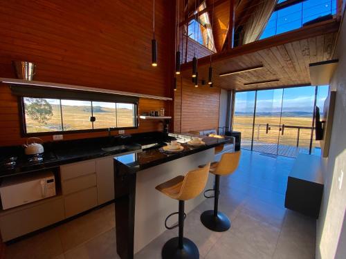 a kitchen with a large island with two stools at Cabanas Arroio Da Serra in Cambara do Sul