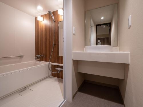 a bathroom with a sink and a tub and a mirror at Hotel Vista Matsuyama in Matsuyama