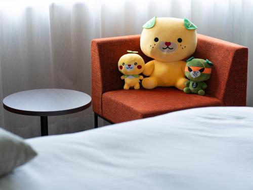 two stuffed animals sitting on a chair in a room at Hotel Vista Matsuyama in Matsuyama