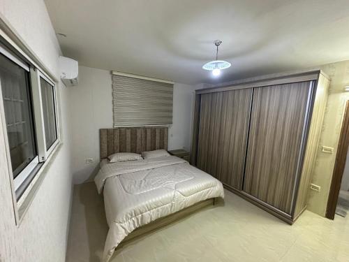 a bedroom with a bed and a large window at شقه مفروشه بمدخل مستقل و موقف لثلاث سيارات مع ساحات خارجيه in Irbid