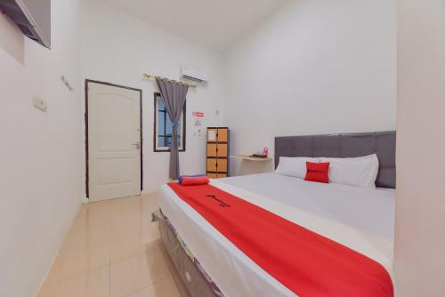 ein Schlafzimmer mit einem großen weißen Bett mit roter Bettwäsche in der Unterkunft Reddoorz near Juwata Airport Tarakan in Tarakan