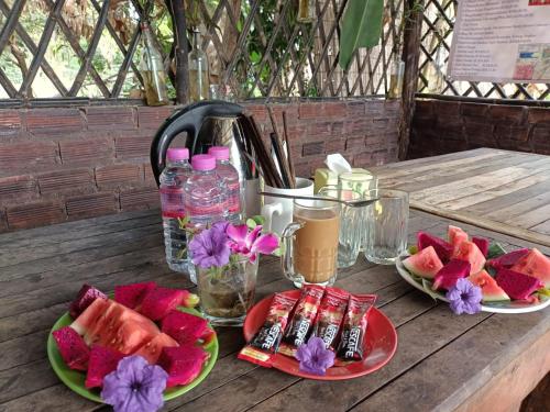 uma mesa de madeira com dois pratos de melancias e bebidas em Phonluer Angkor Homestay, em Siem Reap