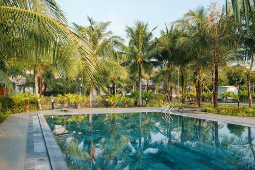 a swimming pool with palm trees in the background at Kosmos Phu Quoc Apart Hotel in Phu Quoc