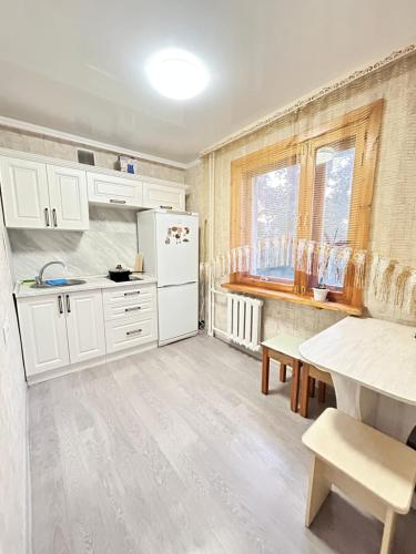 La cuisine est équipée de placards blancs et d'un réfrigérateur blanc. dans l'établissement 2 комнатная квартира магазин Айналайын по Ауельбекова, à Kökşetaw