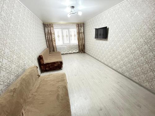 Cette chambre vide dispose d'un canapé et d'une télévision murale. dans l'établissement 2 комнатная квартира магазин Айналайын по Ауельбекова, à Kökşetaw