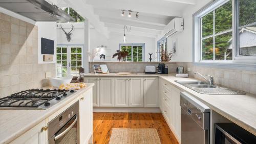 a kitchen with white cabinets and a stove top oven at Dove Cottage in Bundanoon