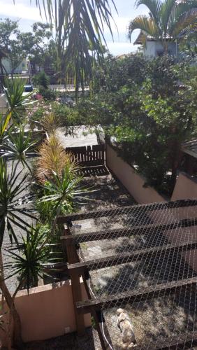 a garden with palm trees and a fence at Linda Casa no Jardim Mariléa com Área Gourmet e Hidromassagem! in Rio das Ostras