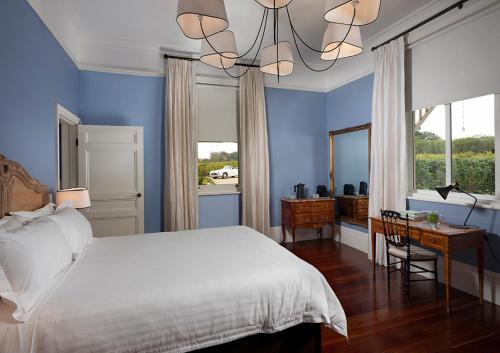 Dormitorio azul con cama blanca y escritorio en Le Mas Barossa en Rowland Flat