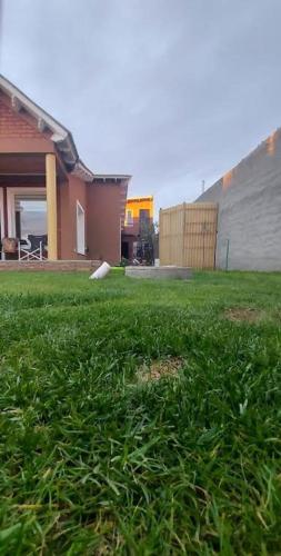 a yard with green grass in front of a house at Los alamos in Río Gallegos