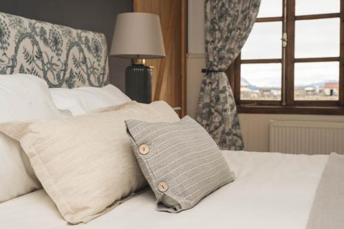a bed with a pillow on it with a window at Bories - Boutique Guest House in Puerto Natales