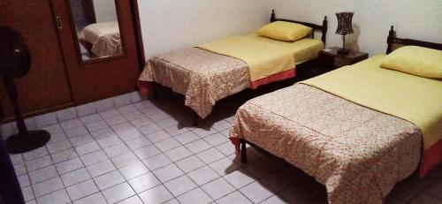 een hotelkamer met twee bedden en een spiegel bij Hostal Iberia in Talara