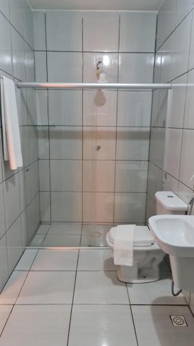 a white bathroom with a toilet and a sink at Pousada Nativos in Baía Formosa