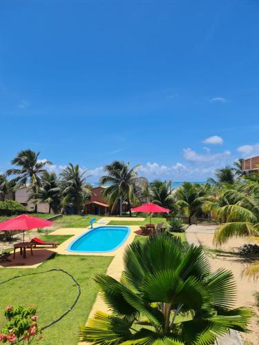 a resort with a pool and palm trees and red umbrellas at Pousada Nativos in Baía Formosa