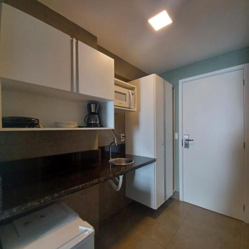 a kitchen with white cabinets and a counter top at ILUSION FLAT-Ponta Negra in Natal