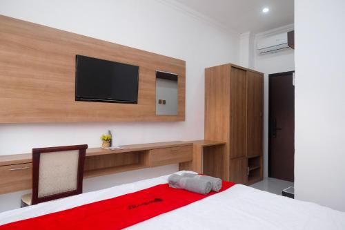 a bedroom with a bed with a tv on the wall at RedDoorz near Sleman City Hall Yogyakarta in Yogyakarta