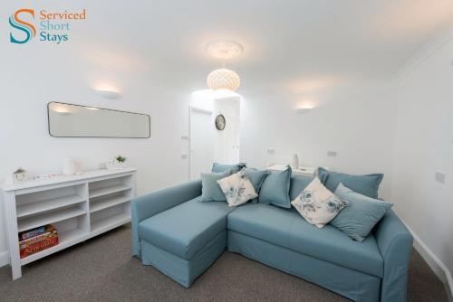 a living room with a blue couch with pillows at Stylish ground floor apartment in Margate