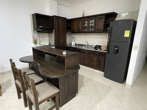 a kitchen with a black refrigerator and a table and chairs at Para buenos gustos, buen confort in Tumba