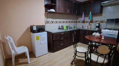 a small kitchen with a table and a white refrigerator at "La #4 Mi Casa es tu Casa"Apt #1 Giron, Azuay,Ecuador 