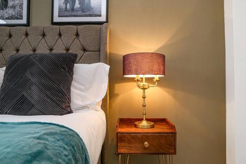 a lamp on a night stand next to a bed at Detached House with Free Parking, Super-Fast Wifi, SmartTV and Garden by Yoko Property in Milton Keynes