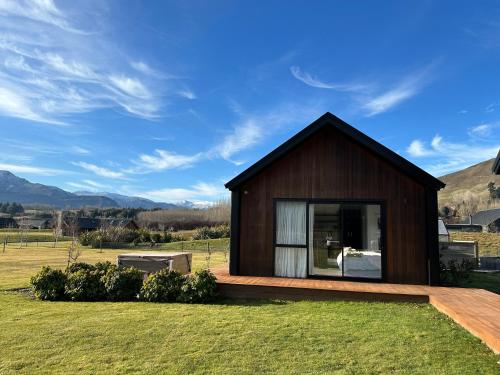 a small wooden house on a grass field at Guest House with a Stunning View in Frankton Wharf
