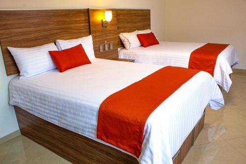 two beds in a hotel room with red and white sheets at La Casa del Reloj - Zona de Hospitales in Mexico City