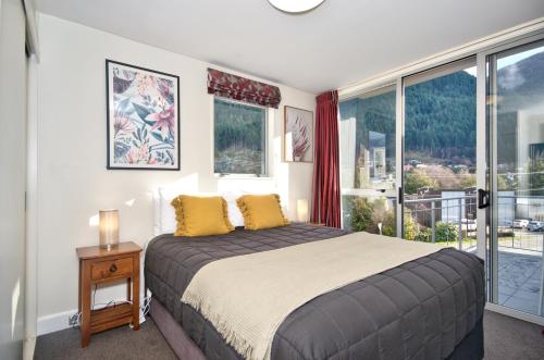 a bedroom with a bed and a large window at The Whistler Holiday Apartments in Queenstown