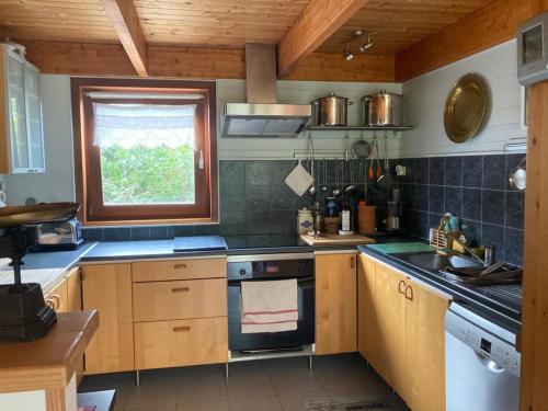 une cuisine avec des armoires en bois et un four à plaques de cuisson dans l'établissement Maison familiale, proche plage et nature, idéale pour 8 personnes avec jardin et équipements complet - FR-1-418-233, à Locmaria