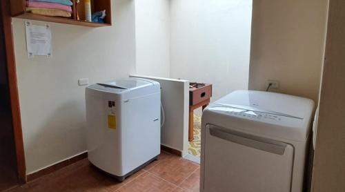 a small kitchen with a refrigerator and a washer at "La #4 Mi Casa es tu Casa" Apt#2 Girón, Azuay, Ecuador 