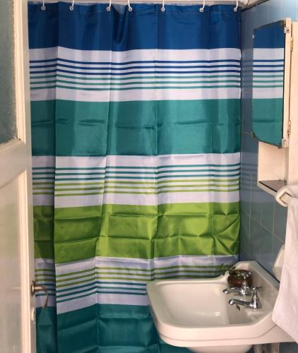 y baño con cortina de ducha y lavamanos. en La Colonial en Salta