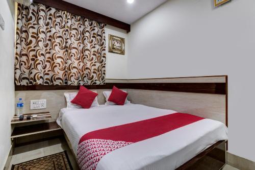 a bedroom with a bed with a red and white blanket at OYO Hotel Satguru in Jamshedpur