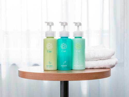 two bottles of soap and towels on a shelf at Sotetsu Fresa Inn Kobe Sannomiya in Kobe