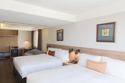 a hotel room with two beds and a kitchen at Just Sleep Kaohsiung Zhongzheng in Kaohsiung