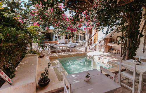 um pátio com uma piscina com mesas e flores em LunArena Boutique Beach Hotel Yucatan Mexico em El Cuyo