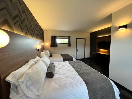 Cette chambre d'hôtel comprend 2 lits avec des oreillers blancs. dans l'établissement Manitoulin Motel, à Little Current