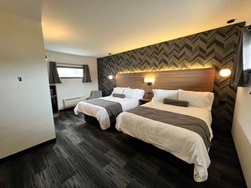 une chambre d'hôtel avec deux lits et une grande tête de lit dans l'établissement Manitoulin Motel, à Little Current