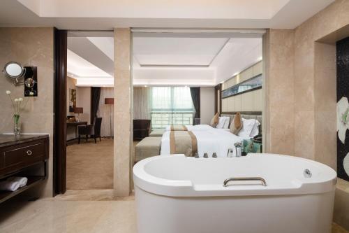 a large bathroom with a tub and a bedroom at Maoming International Hotel in Maoming