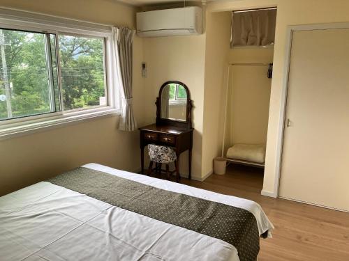 a bedroom with a bed and a dresser and a mirror at Kotori Cottage in Hakuba
