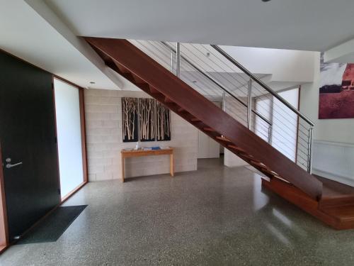 a hallway with a wooden staircase and a table at Beach Haven in Point Lonsdale