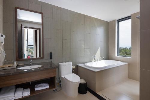 La salle de bains est pourvue d'un lavabo, d'une baignoire et de toilettes. dans l'établissement Le Palmier Ho Tram Resort, à Ho Tram