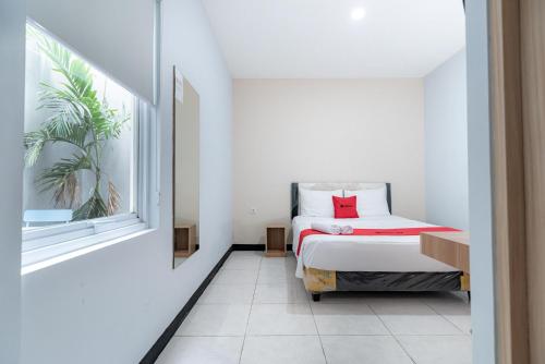 a small bedroom with a bed and a window at RedDoorz near Puri Indah Lippo Mall 2 in Jakarta